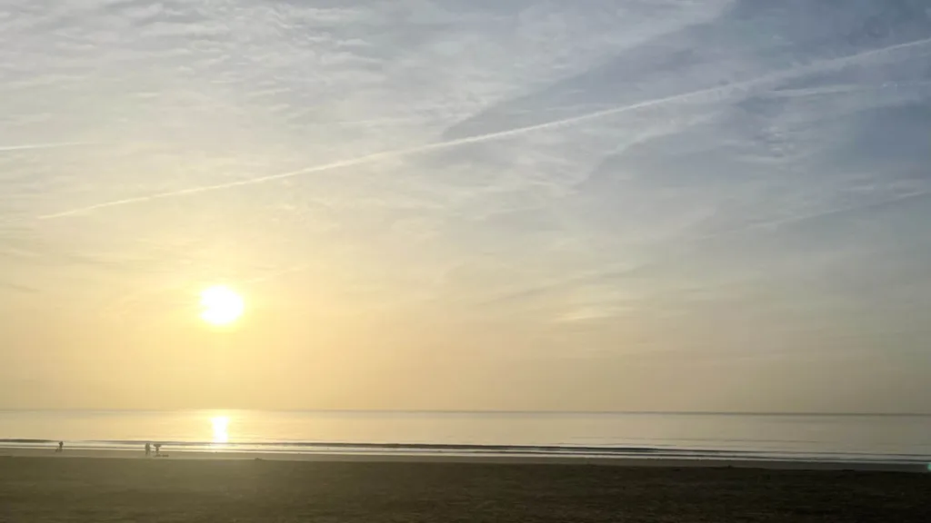 Swansea Bay Beach at sunrise with swimmers in the distance